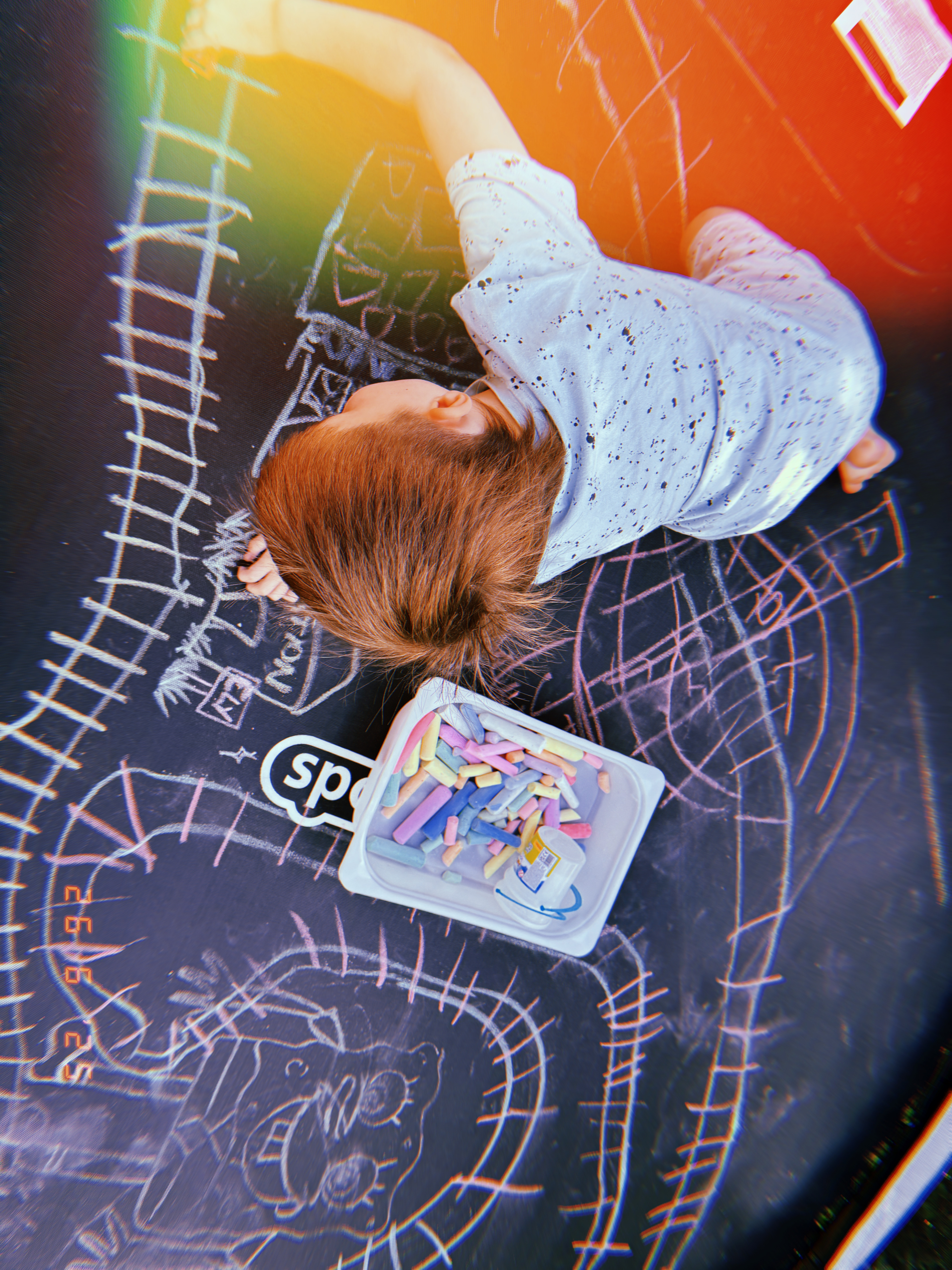 child drawing with chalk on trampoline